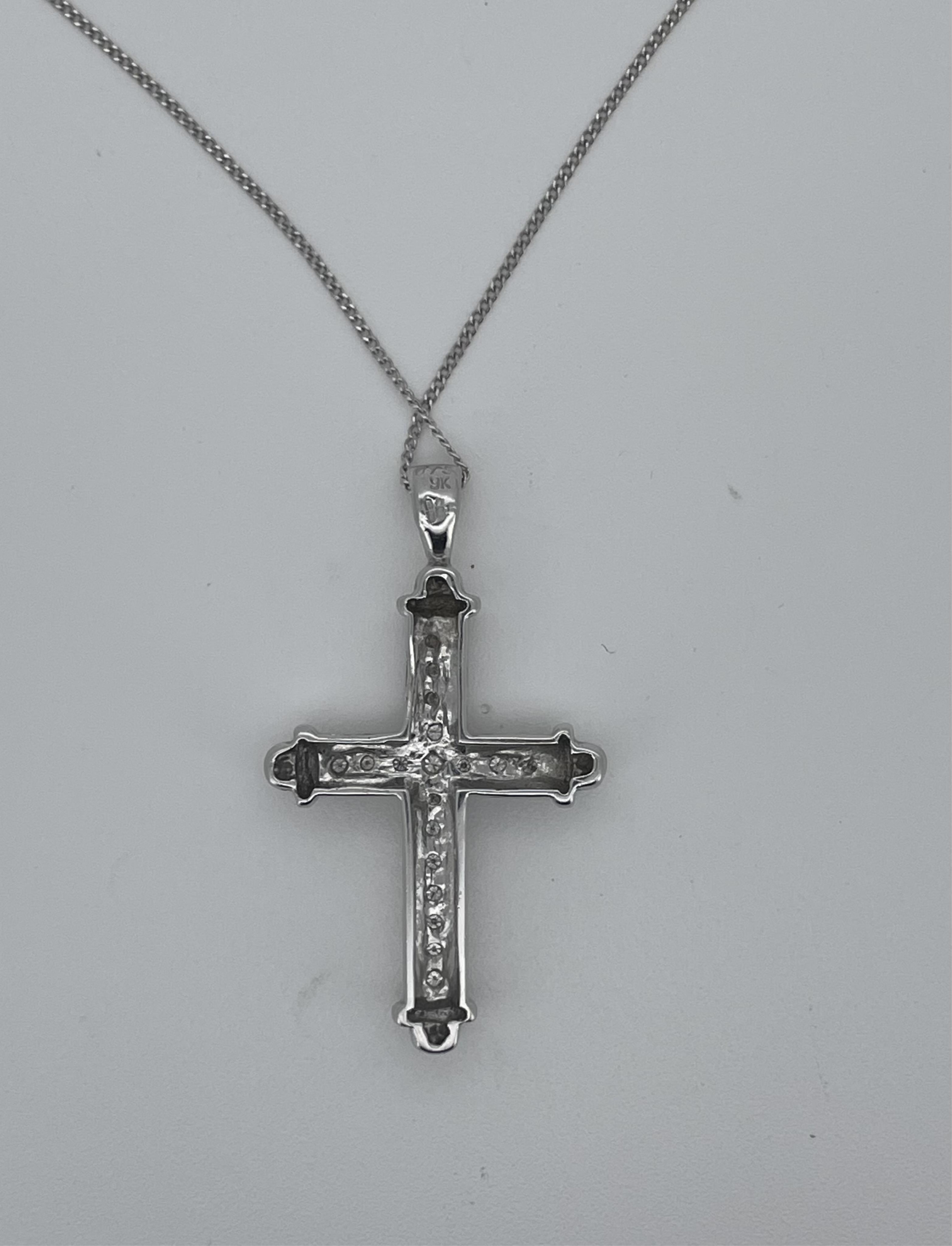 A modern 9ct white gold and diamond chip cluster set cross pendant, overall 36mm, on a white metal fine link chain stamped 375, 48cm.